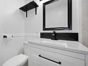 Bathroom featuring toilet, tile walls, and vanity