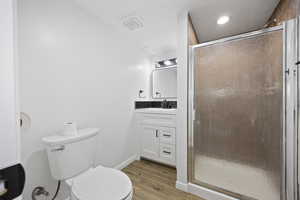 Bathroom with hardwood / wood-style floors, toilet, vanity, and walk in shower