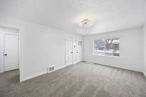 Carpeted spare room with a textured ceiling