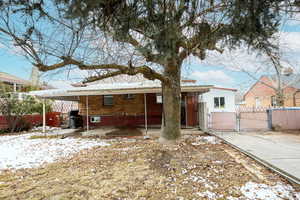 Snow covered back of property featuring a carport