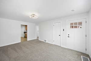 Unfurnished bedroom featuring ensuite bath, carpet floors, and a textured ceiling