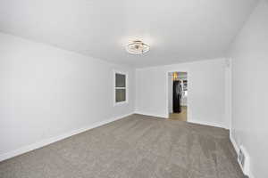 Empty room with carpet floors and a textured ceiling