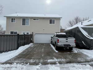 Snow covered house featuring driveway and an attached garage