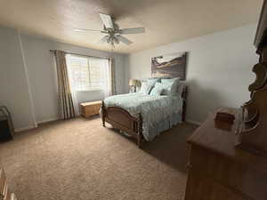 Bedroom with ceiling fan, carpet flooring, and a textured ceiling