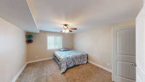 Bedroom with a textured ceiling, ceiling fan, and light colored carpet