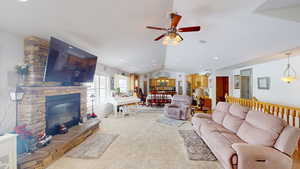 Carpeted living room featuring a fireplace, ceiling fan, and vaulted ceiling