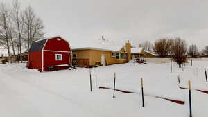 Yard layered in snow featuring an outdoor structure