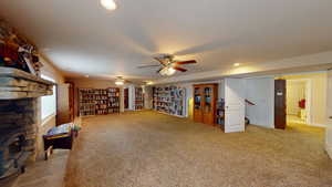 Living area with a wood stove, carpet flooring, and ceiling fan