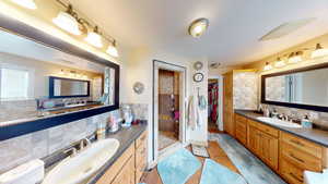 Bathroom with a shower, vanity, and backsplash