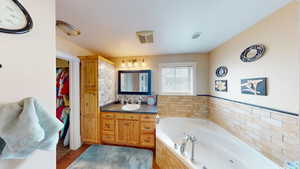 Bathroom with vanity and tiled tub