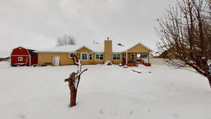 Snow covered rear of property featuring an outbuilding