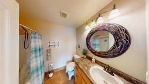 Bathroom with a shower with shower curtain, vanity, and toilet