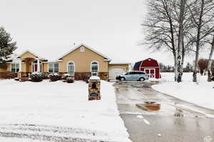 View of front of house with stone siding, concrete driveway, a barn, and stucco siding