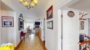 Hallway featuring light tile patterned flooring and a chandelier