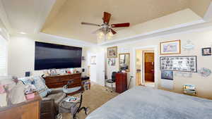 Bedroom featuring a tray ceiling, ceiling fan, crown molding, and carpet