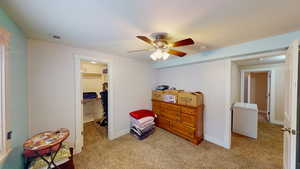 Carpeted bedroom featuring a spacious closet, ceiling fan, and a closet