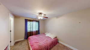 Carpeted bedroom with ceiling fan and a textured ceiling