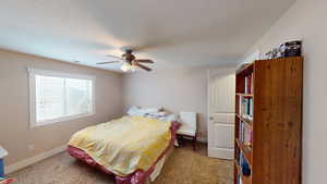 Bedroom with a textured ceiling, light colored carpet, and ceiling fan