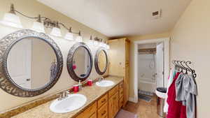 Bathroom featuring a textured ceiling, vanity, and tub / shower combination