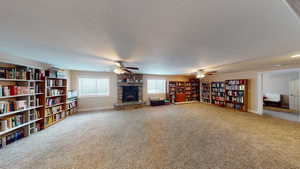 Interior space with a fireplace, ceiling fan, carpet, and a textured ceiling