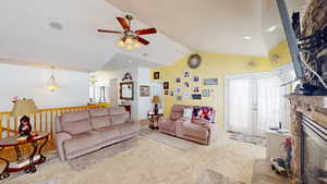 Living room with light carpet, vaulted ceiling, ceiling fan, and a fireplace