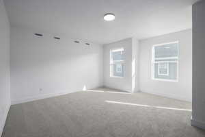 Carpeted spare room featuring baseboards, visible vents, and a textured ceiling