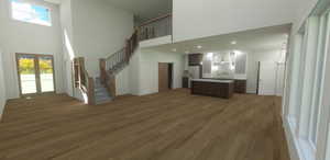 Unfurnished living room featuring french doors, a towering ceiling, and dark hardwood / wood-style flooring