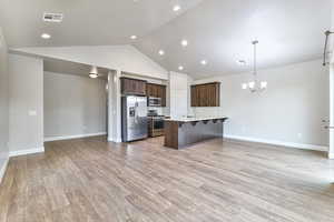 Kitchen featuring a center island with sink, a kitchen bar, a chandelier, pendant lighting, and stainless steel appliances