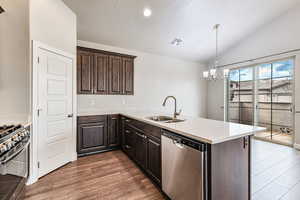 Kitchen featuring appliances with stainless steel finishes, dark wood-type flooring, vaulted ceiling, sink, and kitchen peninsula