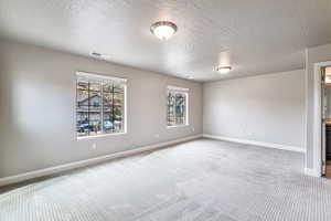 Carpeted empty room with a textured ceiling