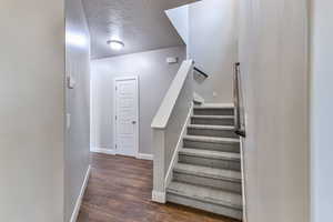 Stairway with wood-type flooring and a textured ceiling