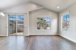 Spare room with an inviting chandelier, wood-type flooring, and lofted ceiling