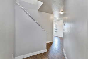 Hall featuring dark hardwood / wood-style flooring and a textured ceiling