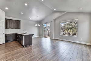 Kitchen with a notable chandelier, decorative light fixtures, sink, dark hardwood / wood-style floors, and kitchen peninsula