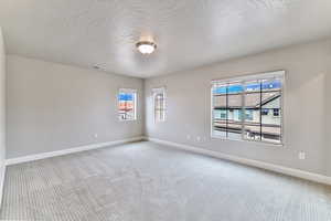 Carpeted spare room featuring a textured ceiling