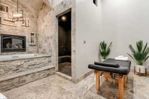 Bathroom with tiled shower, a notable chandelier, and a fireplace