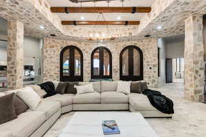 Living room with beam ceiling, a chandelier, and ornate columns