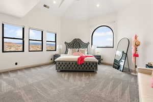 Bedroom with high vaulted ceiling and light colored carpet