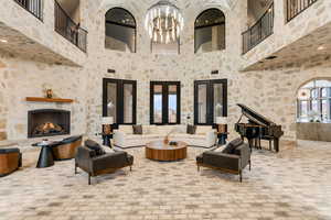 Living room featuring a fireplace, a chandelier, and a high ceiling