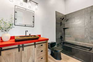 Bathroom with tiled shower / bath combo and vanity