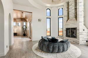 Living room with a large fireplace, wood ceiling, a high ceiling, and light hardwood / wood-style flooring