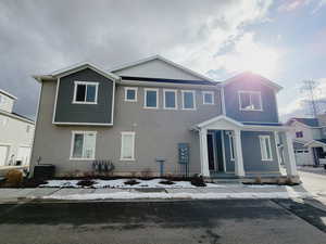 View of front of home with central air condition unit and a garage