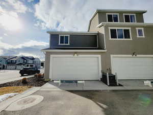 View of front of property featuring a garage and cooling unit