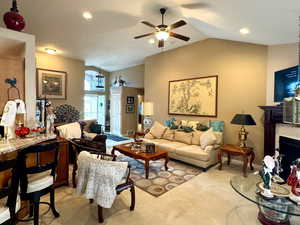 Living room with ceiling fan, carpet flooring, and vaulted ceiling