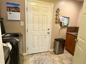 Laundry area featuring light tile patterned floors, washer and dryer, and cabinets