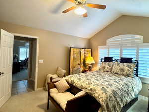 Carpeted bedroom with ceiling fan, a textured ceiling, and lofted ceiling