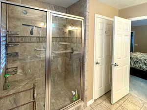 Bathroom featuring a shower with door and a textured ceiling