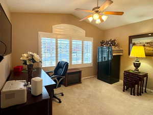 Carpeted office space featuring vaulted ceiling, ceiling fan, and a textured ceiling