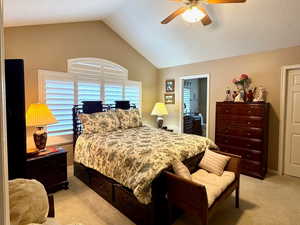 Bedroom featuring ceiling fan, vaulted ceiling, light carpet, and a textured ceiling