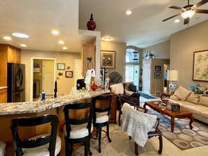 Carpeted living room with a textured ceiling, lofted ceiling, and ceiling fan